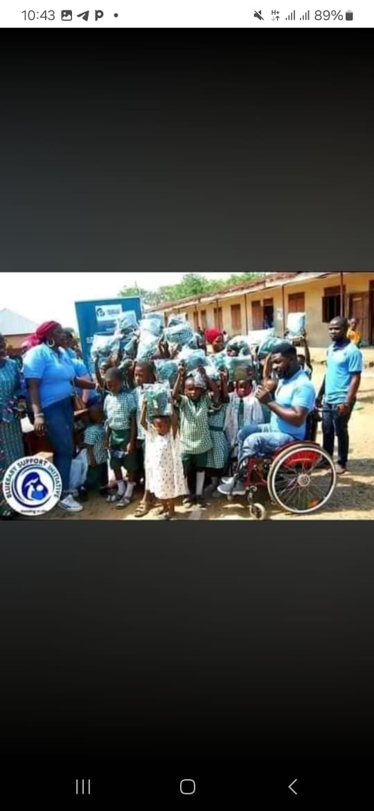 BBSI team, including a volunteer using a wheelchair, celebrating Children's Day with pupils and their new backpacks