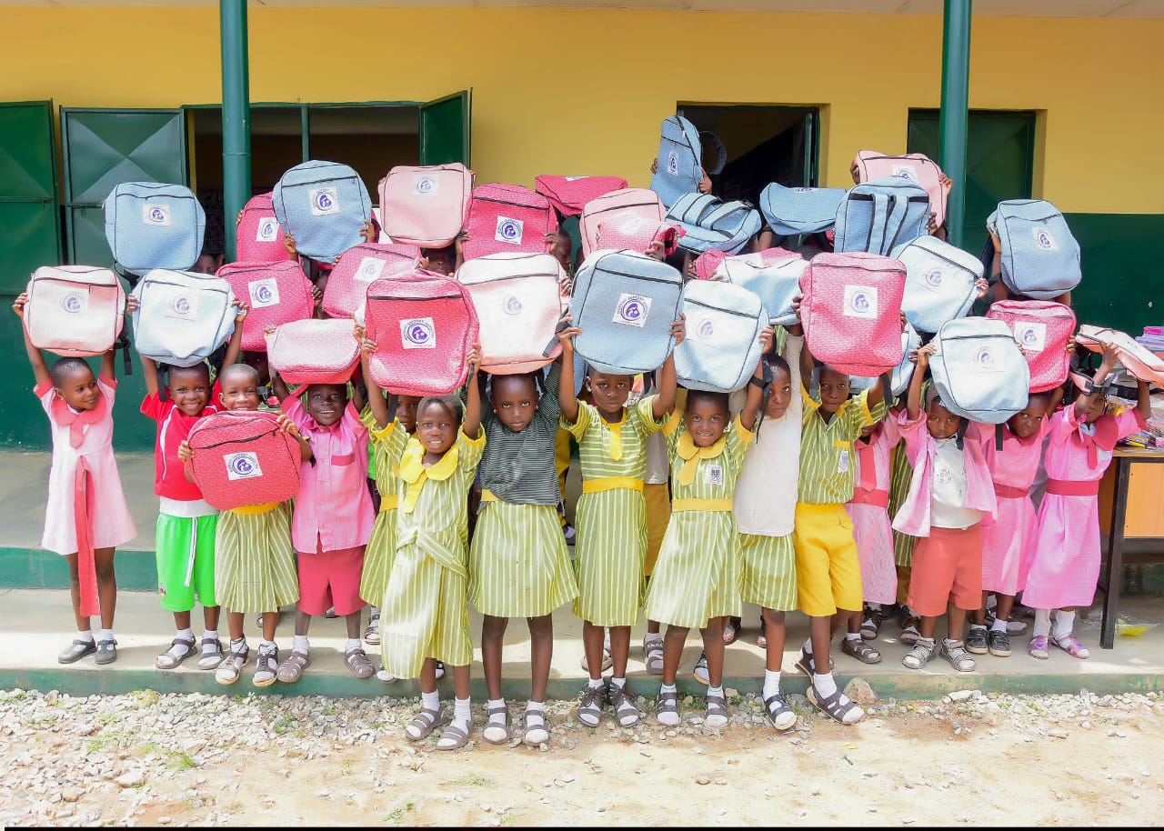 Pupils and BBSI volunteers gathered outdoors with new backpacks