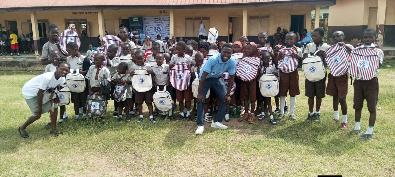 BBSI volunteers, including a volunteer using a wheelchair, celebrating with schoolchildren after a backpack handover