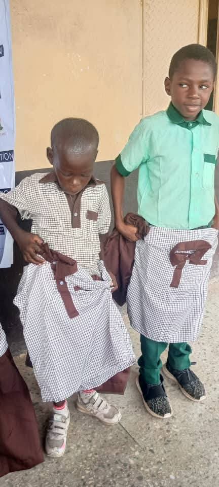 Two boys holding up their new school uniforms