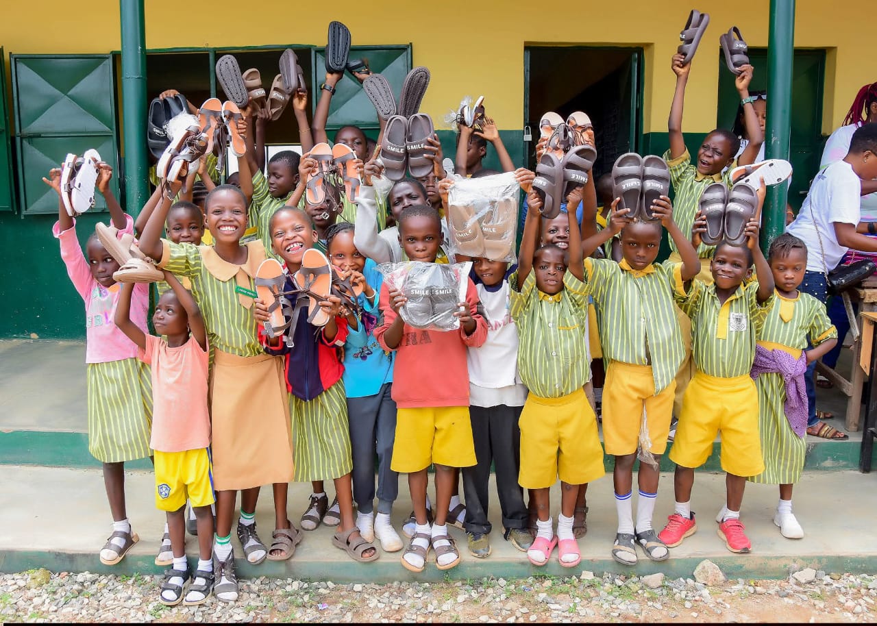 Pupils holding up new pairs of sandals during a footwear distribution