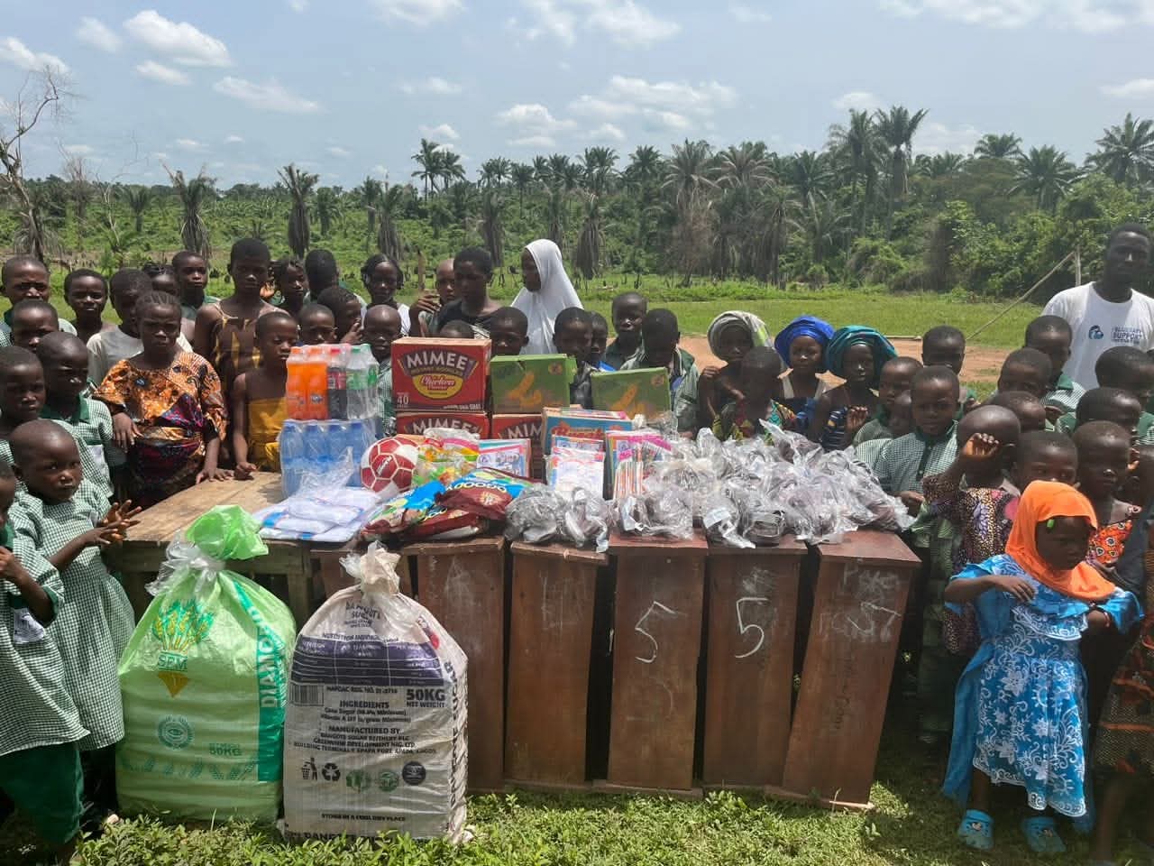 A BBSI volunteer handing school supplies to a young pupil